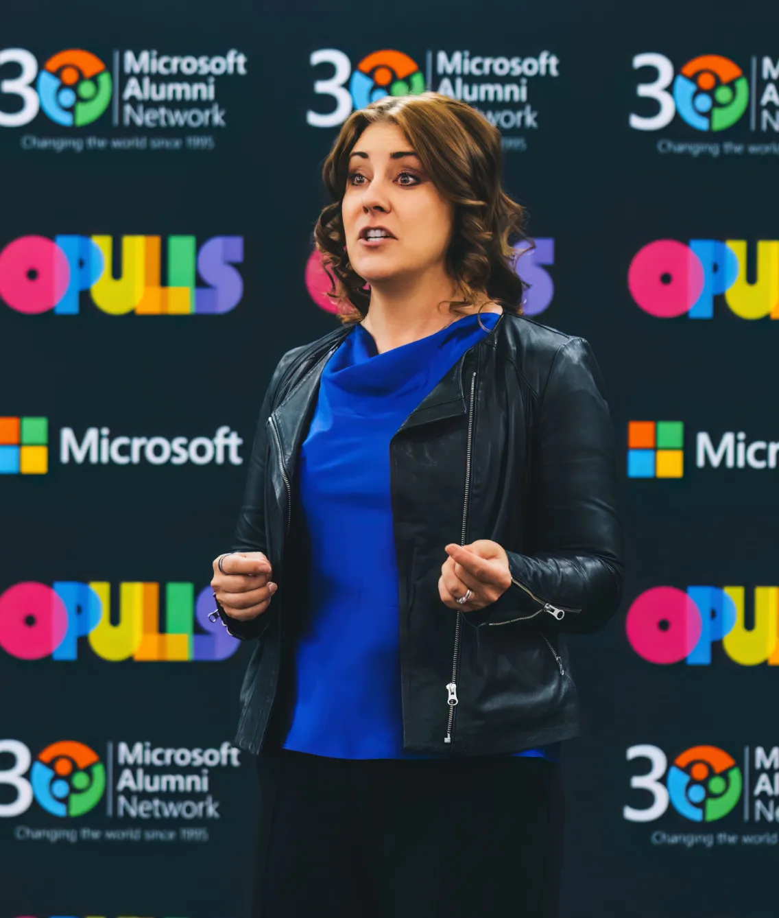 Woman speaking on stage in front of Microsoft event backdrop.