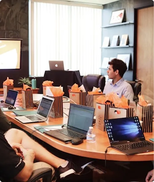 People sitting around a conference table with laptops during a meeting.