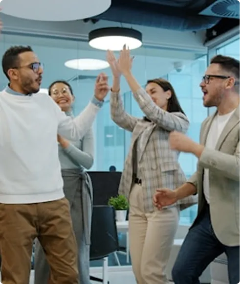 Group of coworkers celebrating and high-fiving in an office.