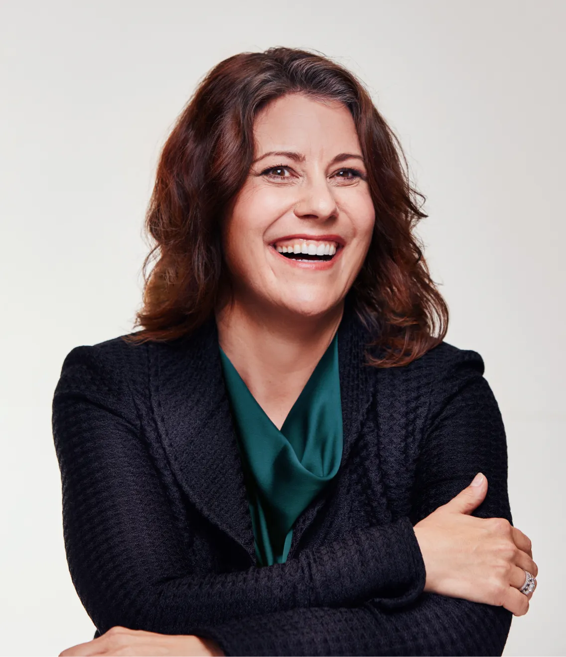 Woman smiling with arms crossed against a light background