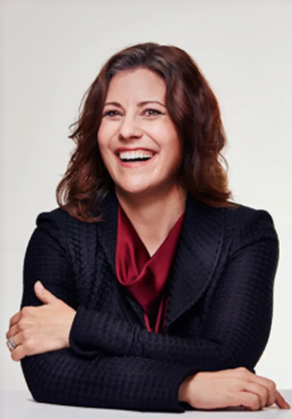 Woman smiling with arms crossed against a light background