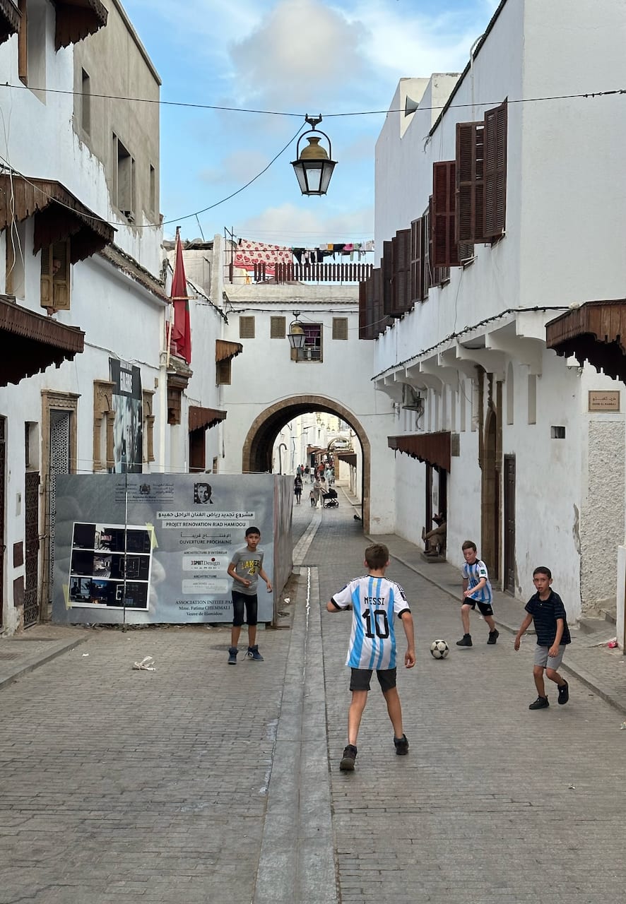 Children play soccer in a narrow whitewashed street
